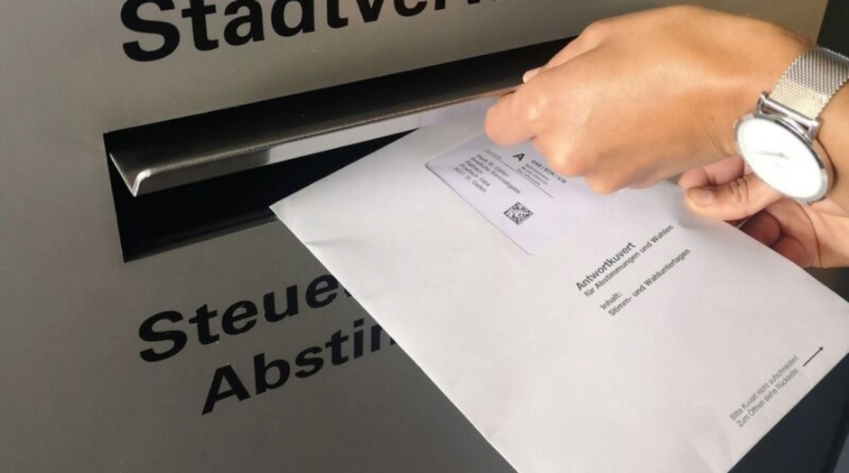 Person legt Abstimmungsunterlagen in Briefkasten